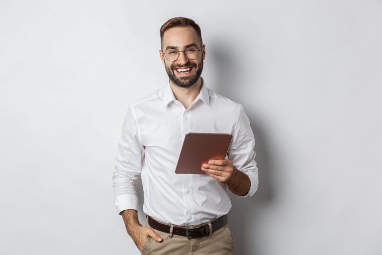 Confident business man holding digital tablet and smiling, standing against white background